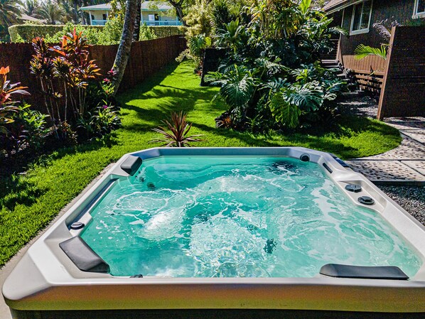 A hot tub in a backyard with a well-maintained lawn and various tropical plants. - Zuki House - 3BR, 2BA Ocean Close, Hot Tub (Pahoa)