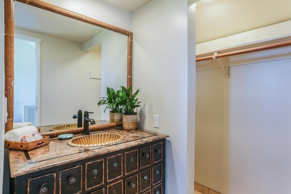 Un baño con un espejo grande, un lavabo con encimera de bambú y un perchero para toallas.