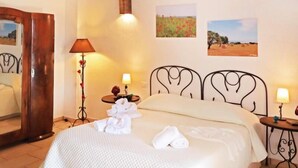 A bedroom with a wooden ceiling, a bed with white linens, two wall-mounted lamps, and two framed pictures on the wall. - Cozy Triple Room with Pool View B&B Diana N.6 (Puglia)