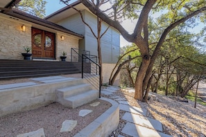 Una casa con fachada de piedra, puerta principal de madera y una escalera que conduce a la entrada.