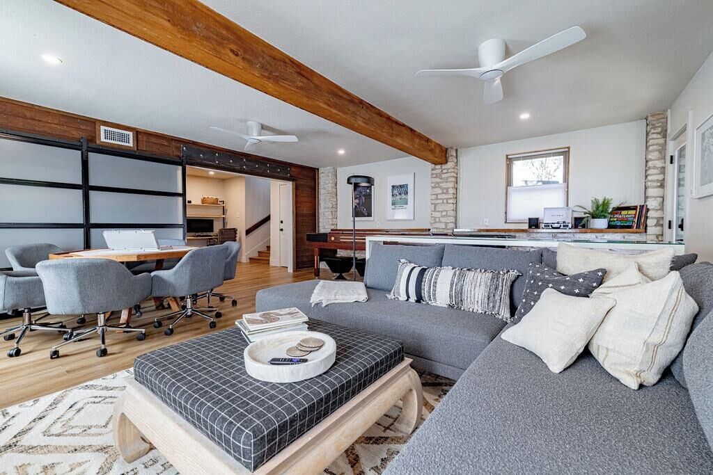 Un salon moderne avec un canapé gris, une table basse et un coin repas avec des chaises.