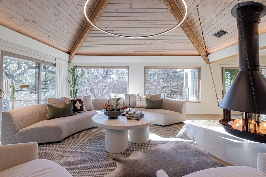 Una sala acogedora con un sofá curvo, una mesa de centro redonda y una chimenea grande.