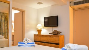 Une chambre d’hôtel avec un lit, un téléviseur fixé au mur, une commode en bois et une lampe.