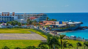 Un hôtel situé sur la côte, composé de plusieurs bâtiments, offrant une vue sur la plage et disposant d’un parking.