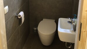 Un baño pequeño con inodoro, lavamanos y una ventana sobre el inodoro.
