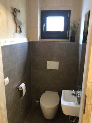 Un bagno piccolo con il water, un lavandino e una finestra sopra il water.