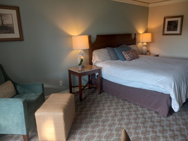 A bedroom with a large bed, bedside lamps, a small table with a vase, a chair, and a patterned carpet. - Paradise by Busch Gardens, walk to beach! Lovely large 3bedroom/3 full bathrooms (Williamsburg)
