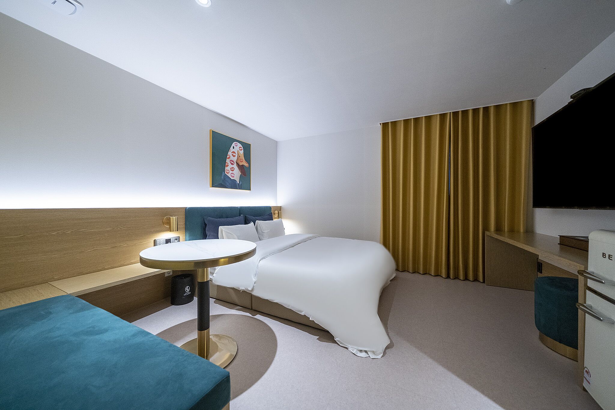 A modern hotel room with a bed, bedside table, and a small desk area.