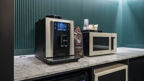 Una cafetera, un microondas y una bolsa de Starbucks sobre una encimera de mármol.