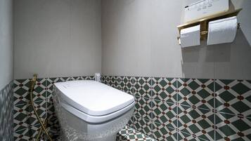 Un baño con inodoro, ducha y toallero.