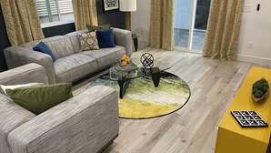 A modern living room with a grey sofa, a glass coffee table, and a yellow accent piece. - Retro Mid-Mod Vibes Getaway (Centrally Located) (Phoenix)