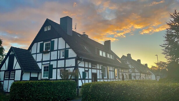 A traditional half-timbered building with a symmetrical facade, a central chimney, and a paved pathway leading to the entrance. - FeWo Siebenstern Fernblick am Hohen Venn (Monschau)