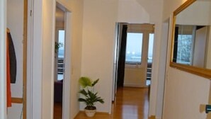 A hallway with wooden flooring, a potted plant, and a mirror on the right wall. - FeWo Siebenstern Fernblick am Hohen Venn (Monschau)