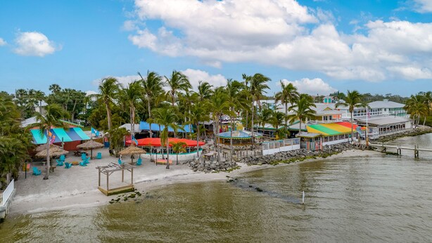 A beachside resort with thatched-roof structures, palm trees, and a waterfront view. - New and sparkly 2/1 on 4 acres! (Sebastian)