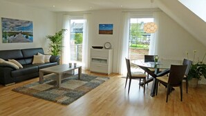 A modern living room with a sofa, coffee table, and dining area. - FeWo Siebenstern Südblick am Hohen Venn (Monschau)