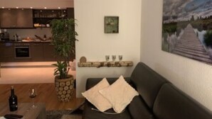 A modern living room with a dark sofa, a coffee table, and a painting on the wall. - FeWo Siebenstern Südblick am Hohen Venn (Monschau)