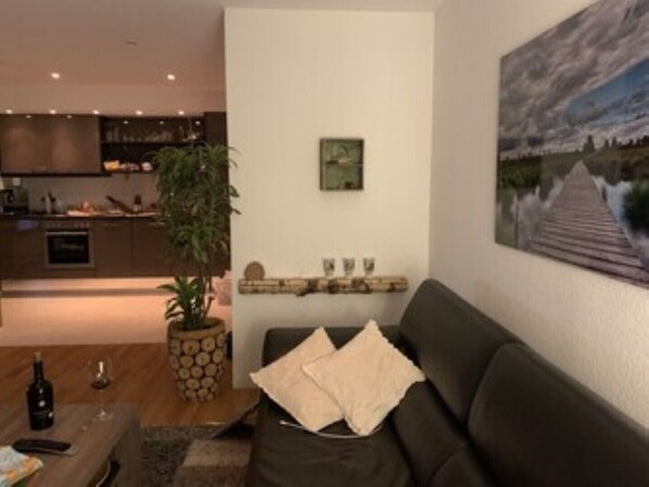 Una sala de estar moderna con un sofá oscuro, una mesa de centro y un cuadro en la pared.