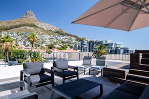 Relax in style with a mountain view from this outdoor seating area, featuring comfortable lounge chairs and a small table.
