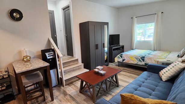 Un dormitorio compacto con cama, televisor, armario, escritorio con silla y una mesita.