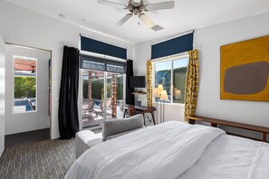 Une chambre d’hôtel équipée d’un lit, d’un bureau, d’une chaise, d’une télévision et offrant une vue sur l’extérieur.