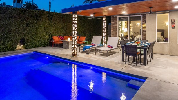 A modern outdoor pool area with lounge chairs, a dining table, and a view of the house. - Veranda Aqua – Colorful Palm Springs Retreat (Palm Springs)