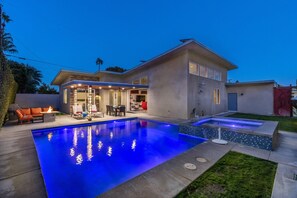 Une maison moderne dotée d’une piscine, d’un espace salon extérieur et d’une terrasse bien éclairée.