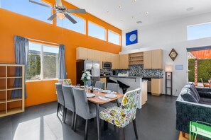 Une cuisine moderne dotée d’un îlot central, un coin repas avec une table et des chaises, et un espace de vie avec un canapé.