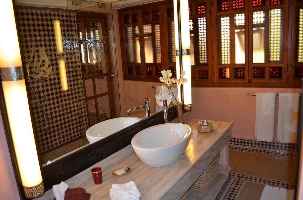 A bathroom with two sinks, a large mirror, and a decorative window with red patterns.