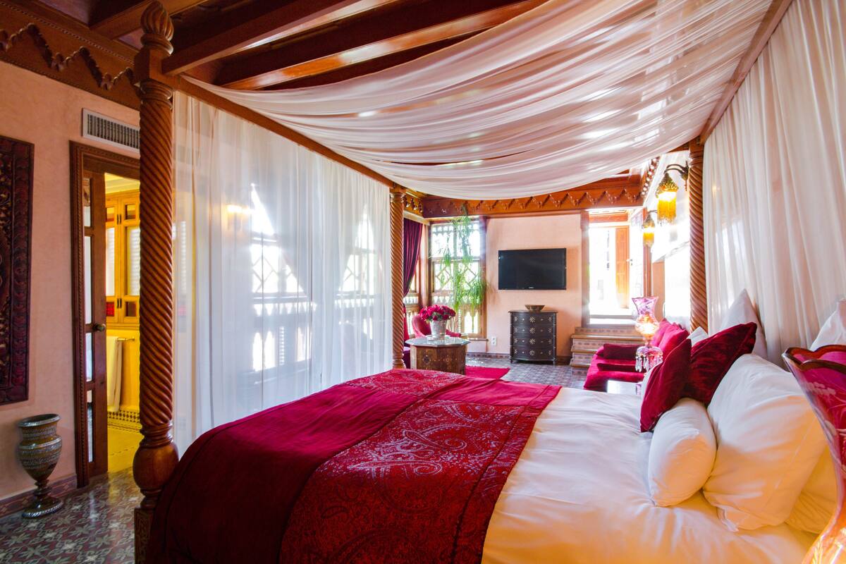 Um quarto espaçoso com uma cama grande, cabeceira de madeira e vista para um pátio.