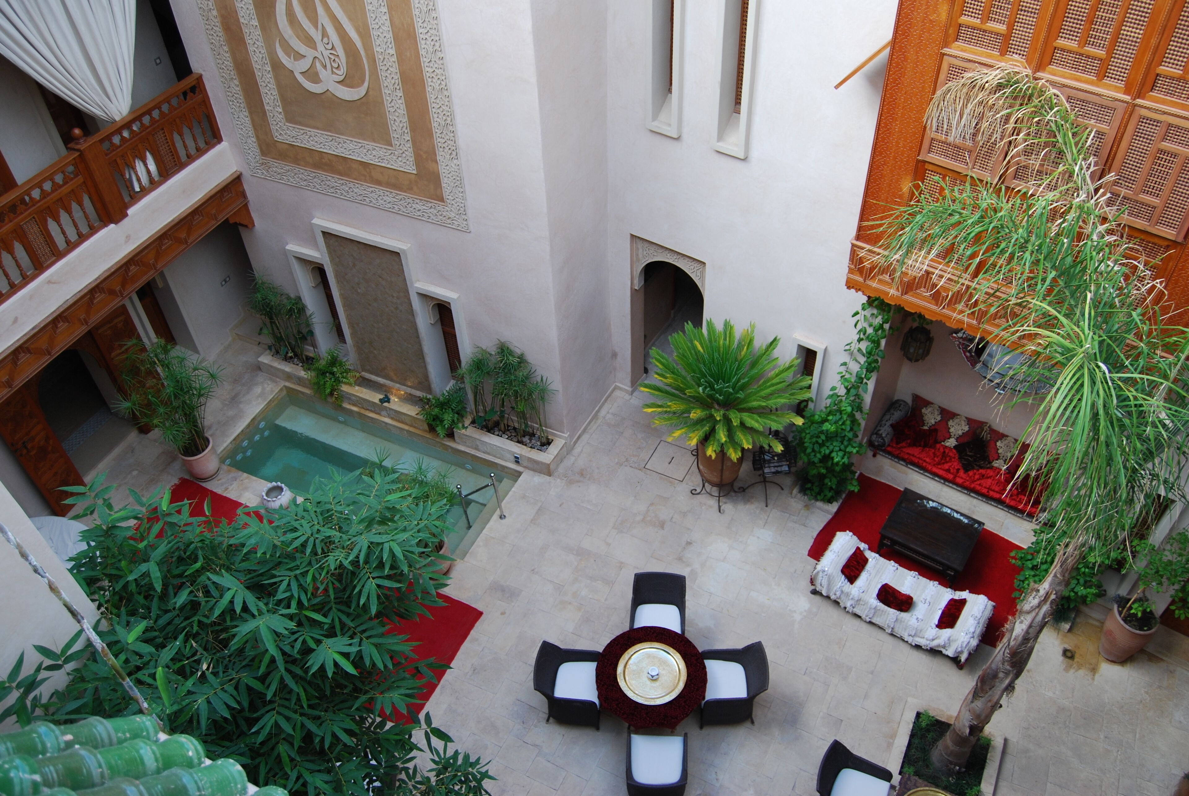 Un patio interior con piscina, zona de estar y plantas en macetas.