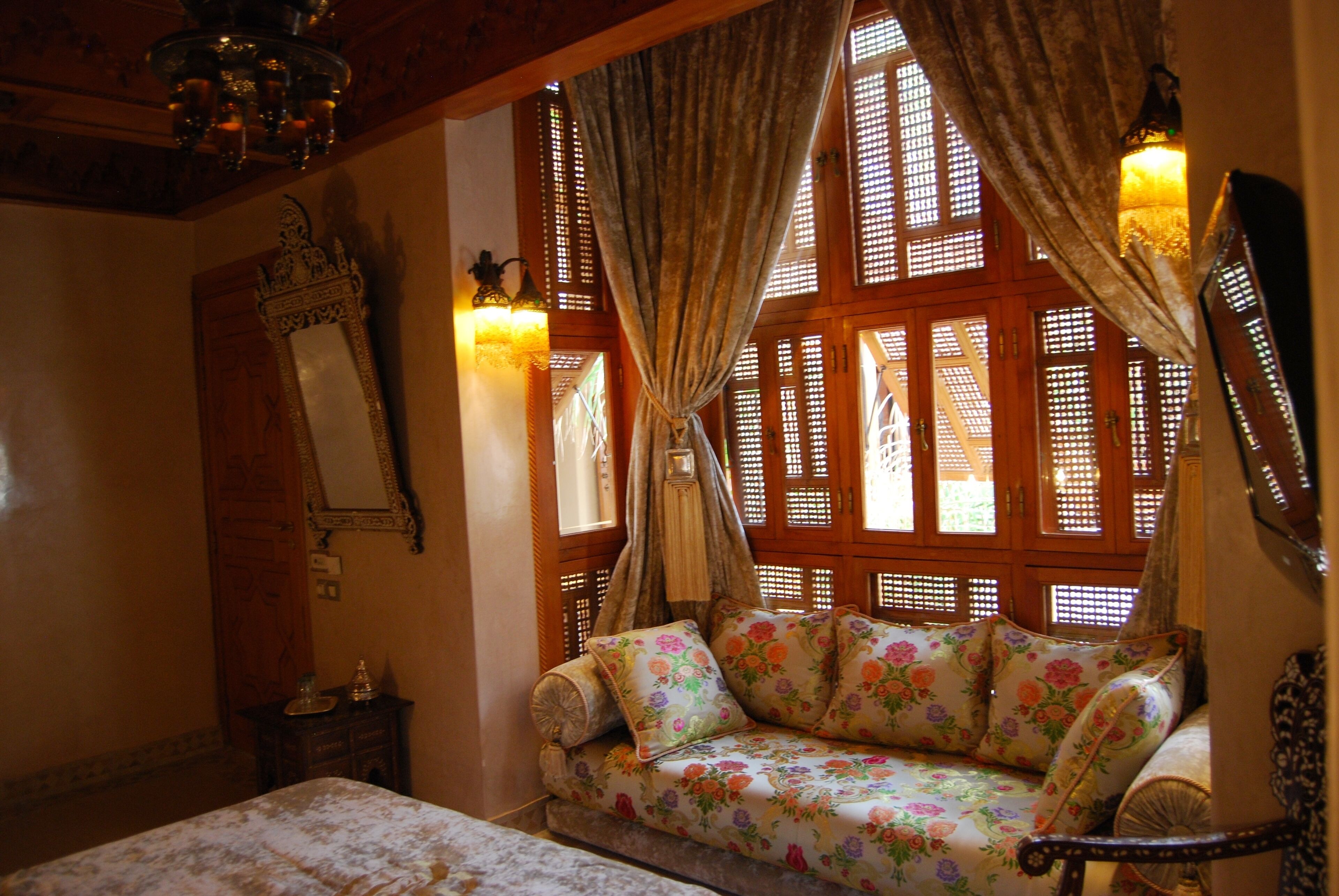 A traditional room with a sofa, a bed, a mirror, and a window with wooden lattice.