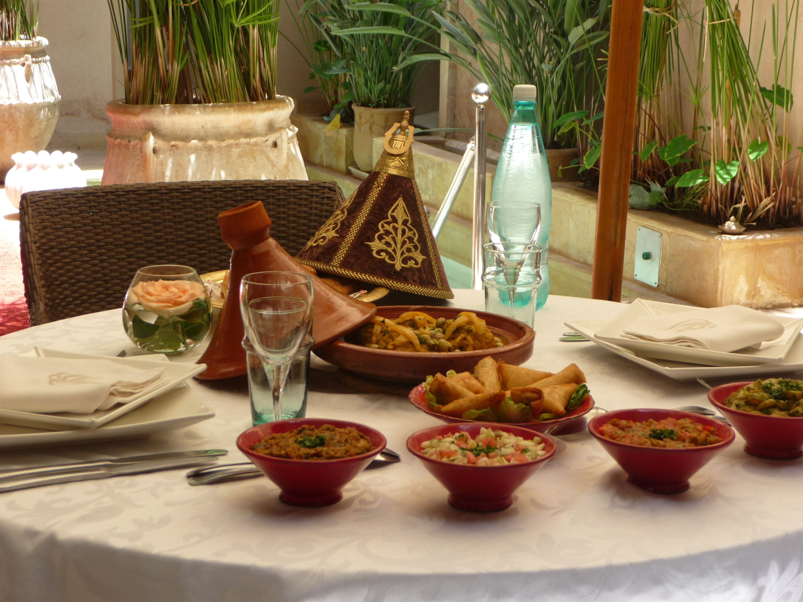 A dining table with various dishes, a water bottle, and a decorative Moroccan tagine.