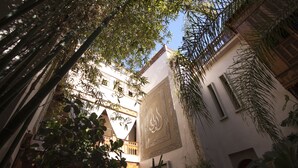 A courtyard with a traditional building featuring arched windows and a decorative wall with calligraphy. - Riad Flam & Spa (Marrakech)
