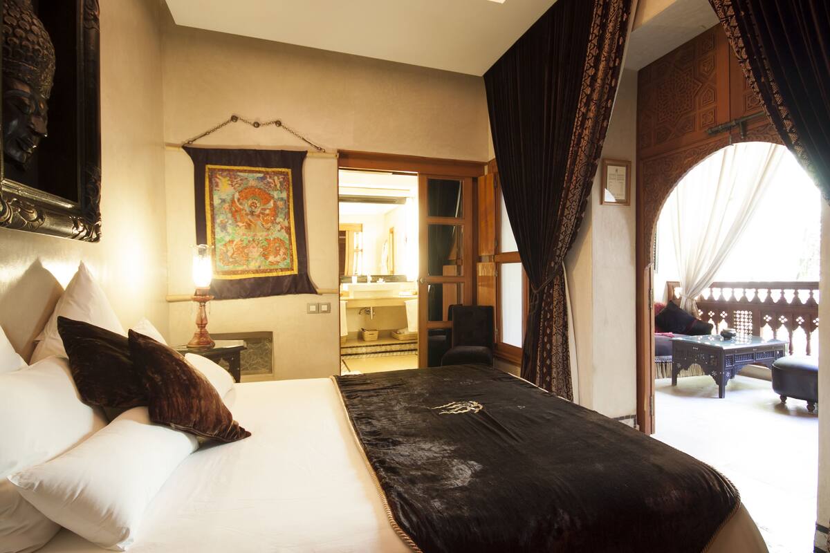 Quarto de hotel com uma cama grande, uma escrivaninha e vista para a varanda.