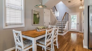 A dining area with a wooden table and white chairs, a staircase, and a kitchen with a stainless steel refrigerator. - Great views, close to cabana club, golf cart included - 23 Veranda Beach (Fripp Island)