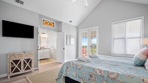 A bedroom with a bed, a TV, a wooden cabinet, and a door leading to a bathroom. - Great views, close to cabana club, golf cart included - 23 Veranda Beach (Fripp Island)