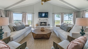 A spacious living room with a fireplace, two sofas, a coffee table, and a television.