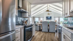 A modern kitchen with a large island, stainless steel appliances, and a view of the ocean.