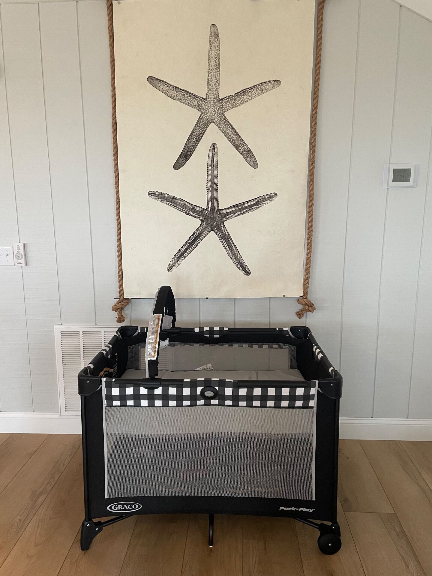 Un carrito Graco con estampado de cuadros y una decoración de estrella de mar en la pared.