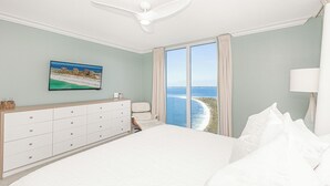 Un dormitorio con una cama grande, un aparador, un televisor y vistas al océano.
