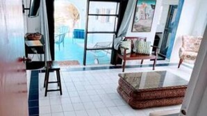 A living room with a tiled floor, a sofa, a coffee table, and a view of the outside. - Villa Kaiae (The Valley)