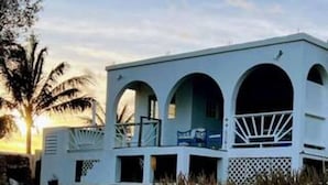 A white building with three arched windows and a balcony. - Villa Kaiae (The Valley)