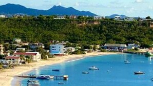 A coastal town with a beach, boats, and a mountain in the background. - Villa Kaiae (The Valley)