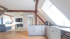 Una cocina moderna con tragaluz, vigas de madera y un comedor con sofá y sillas.