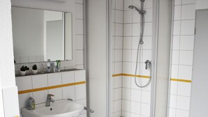 Een badkamer met een wit wastafelmeubel, spiegel en douchecabine.