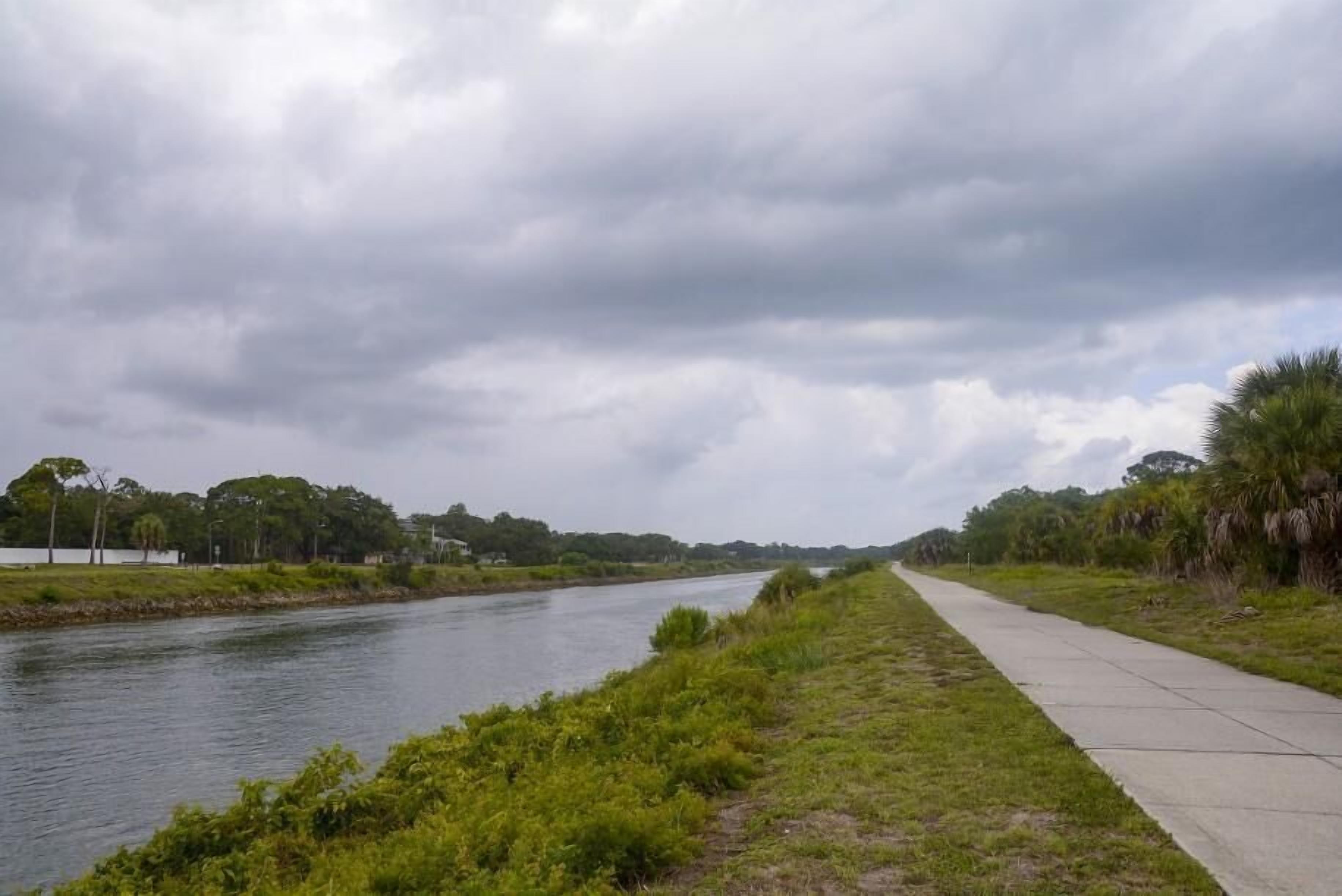 A river with a concrete walkway alongside it.