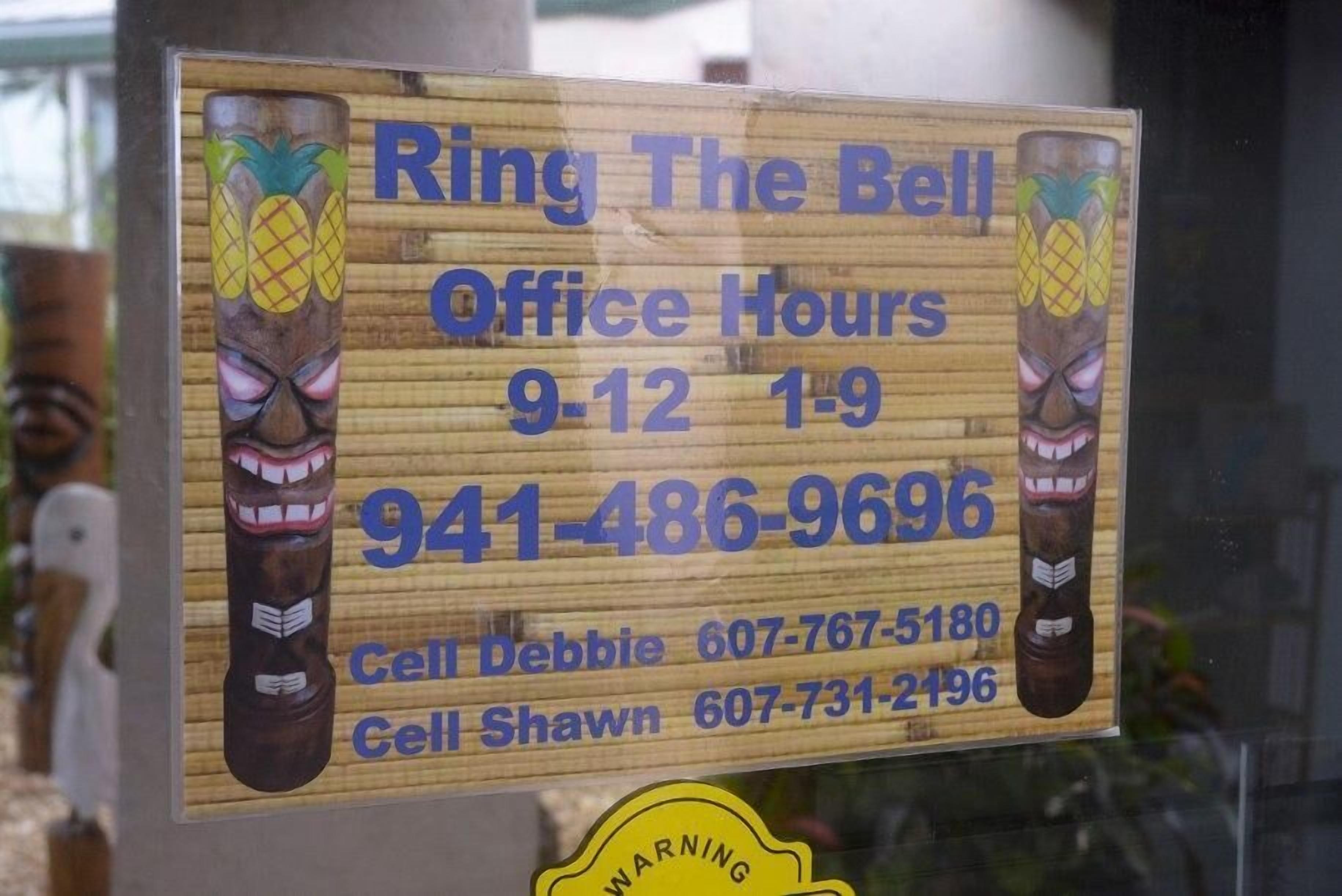 A sign with office hours, contact numbers, and a warning label.