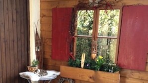 Uma cabana de madeira com janela, uma pequena mesa com um gato, um lampião e uma cesta de lenha.