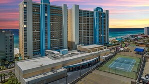 A high-rise hotel with multiple floors, a rooftop pool, and a tennis court. - Cast a Waves 512–Gulf Views–Sleeps 2 (Panama City Beach)