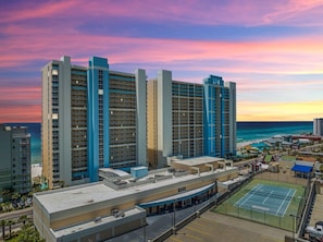 A high-rise hotel with multiple floors, a rooftop pool, and a tennis court.